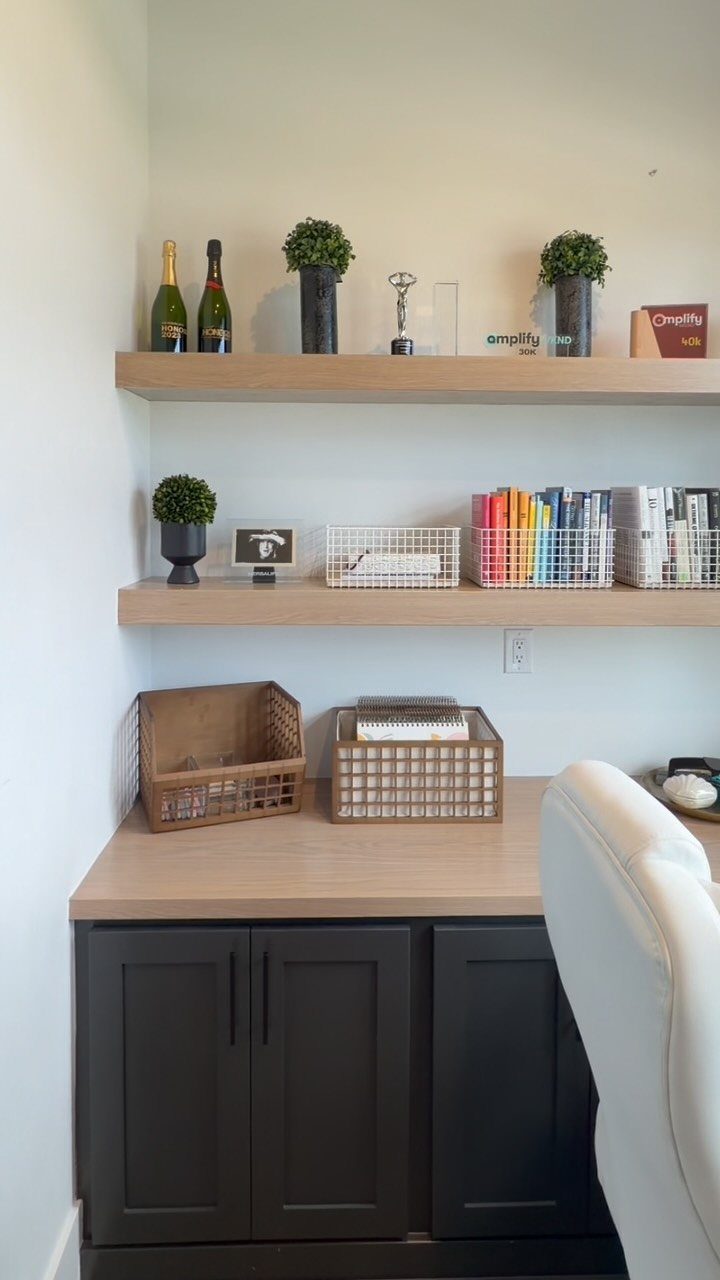 12 Office Storage Room Organization Ideas for Every Layout 2 Organized home office desk with floating wooden shelves, decorative plants, books, and woven storage baskets.