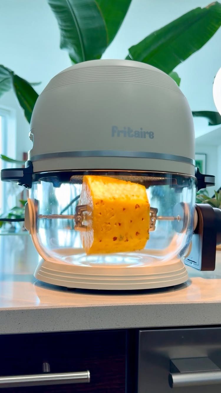 Non Toxic Kitchen Essentials: 10 Pieces That Actually Work 5 A beige Fritaire air fryer with a glass basket cooking a piece of pineapple on a rotisserie spit.