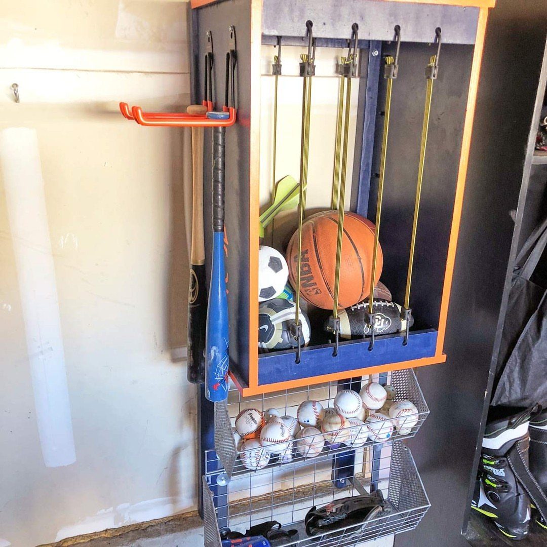 Sports balls held by bungee cords in a wall-mounted blue and orange storage unit.