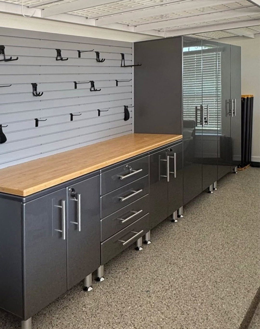 Grey metal garage storage cabinets with a wooden countertop and various drawers and tall units.
