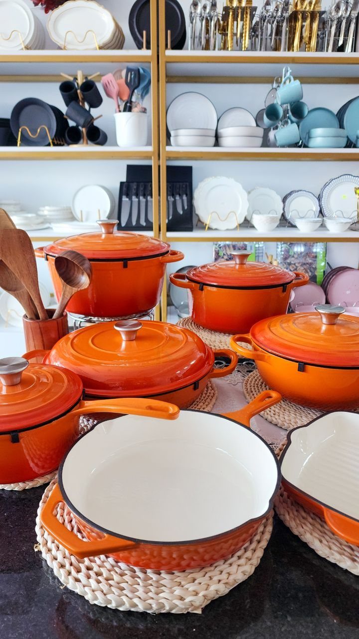 Non Toxic Kitchen Essentials: 10 Pieces That Actually Work 3 Orange enameled cast iron pots and pans arranged on woven trivets on a kitchen counter.