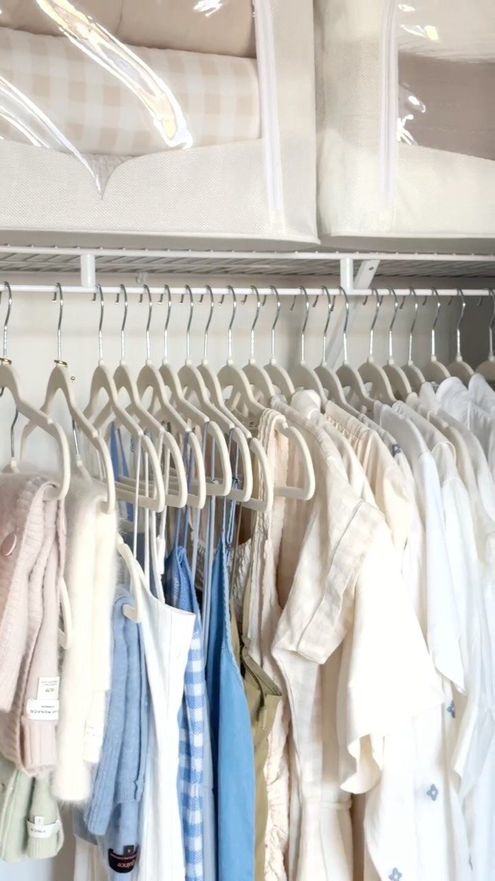 DIY Closet Organization: 16 Ideas for Every Layout 16 White hangers holding light-colored clothing hanging on a rod beneath fabric storage bins in a closet.