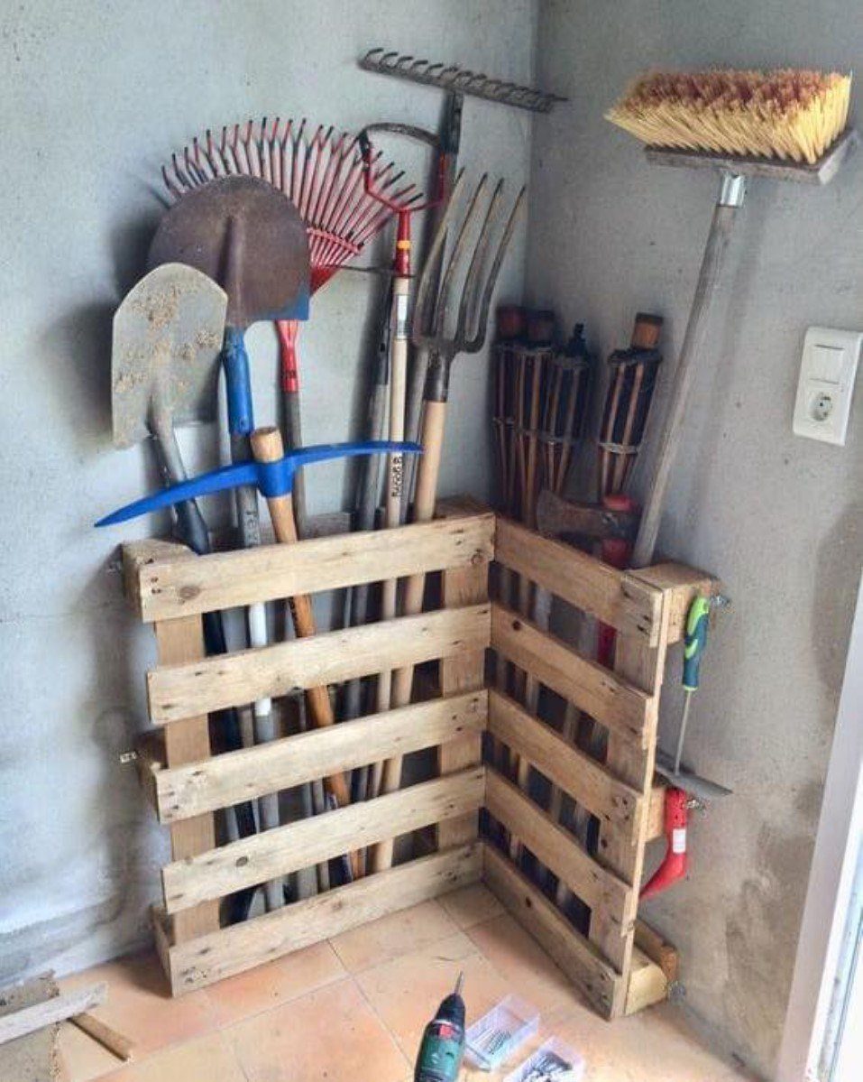11 Tool Shed Storage Ideas for Every Wall and Corner 6 Wooden pallet garden tool holder storing various shovels and rakes in a corner.