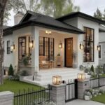 A modern white house with black trim, a cozy front porch, and a manicured garden with a black fence.