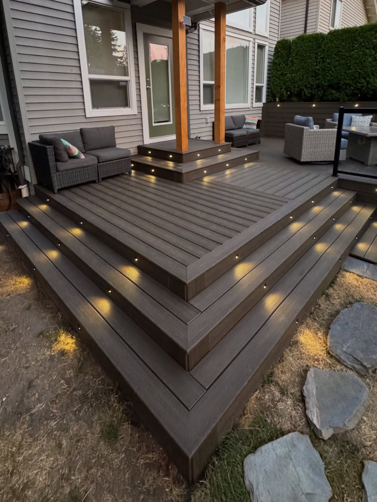 Wooden deck steps with small warm LED accent lights embedded into the risers at dusk.