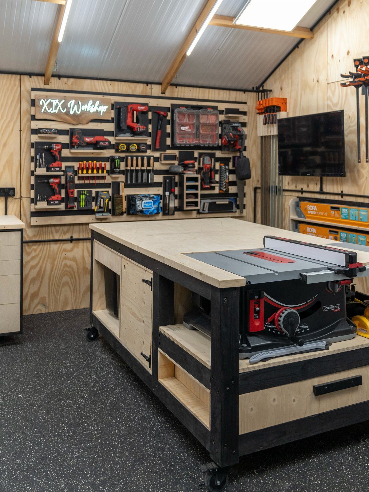 11 Tool Shed Storage Ideas for Every Wall and Corner 5 A wooden rolling workbench with a miter saw mounted on top in a workshop setting.