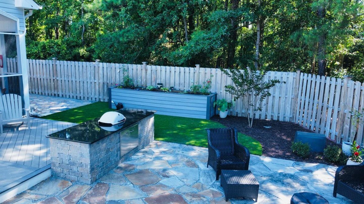 11 Flagstone Patio Design Ideas with Photos for Your Yard 8 Flagstone patio featuring a modern outdoor kitchen island with a dark countertop and stone base.