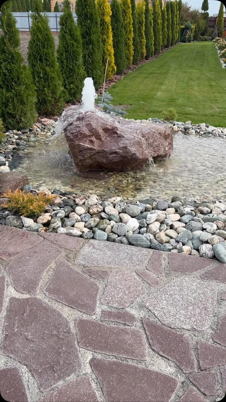 11 Flagstone Patio Design Ideas with Photos for Your Yard 5 A water fountain bubbling over a large rock surrounded by river stones and flagstone patio.