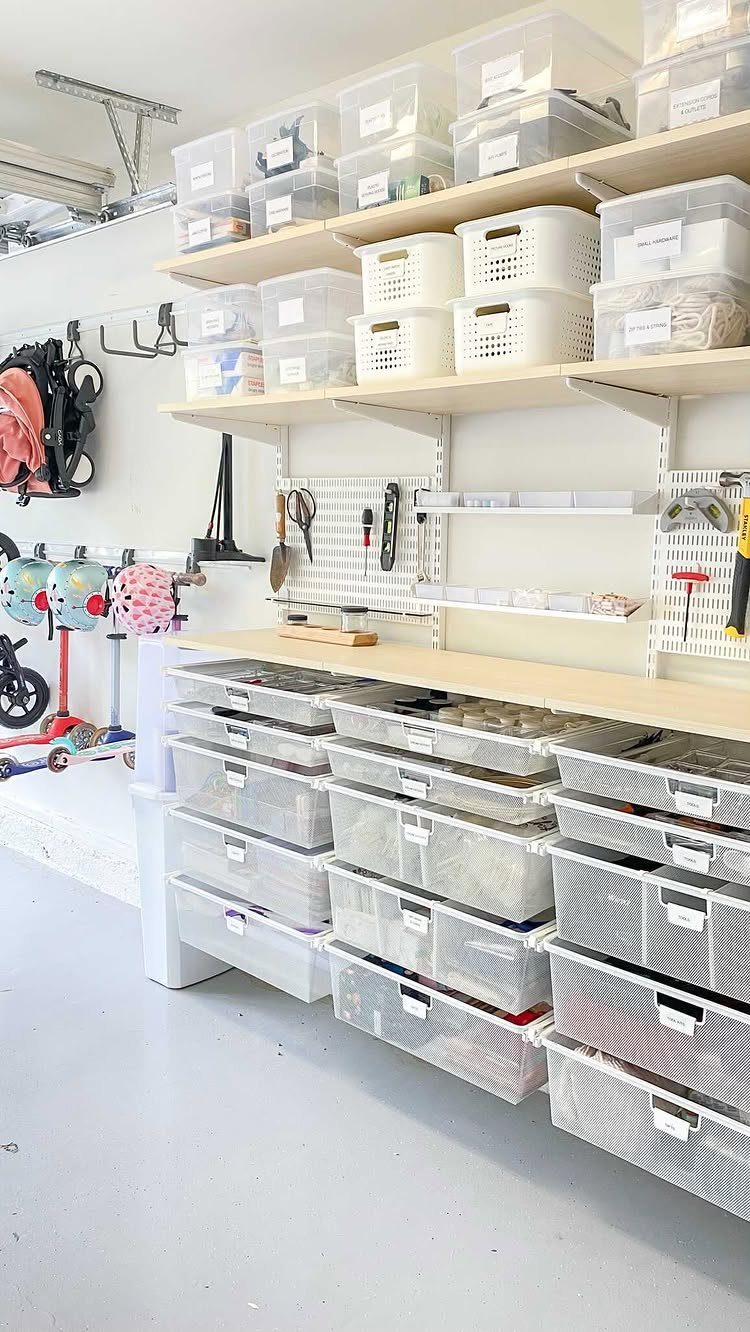 Organized garage storage with clear bins on shelves and large drawers on the floor.