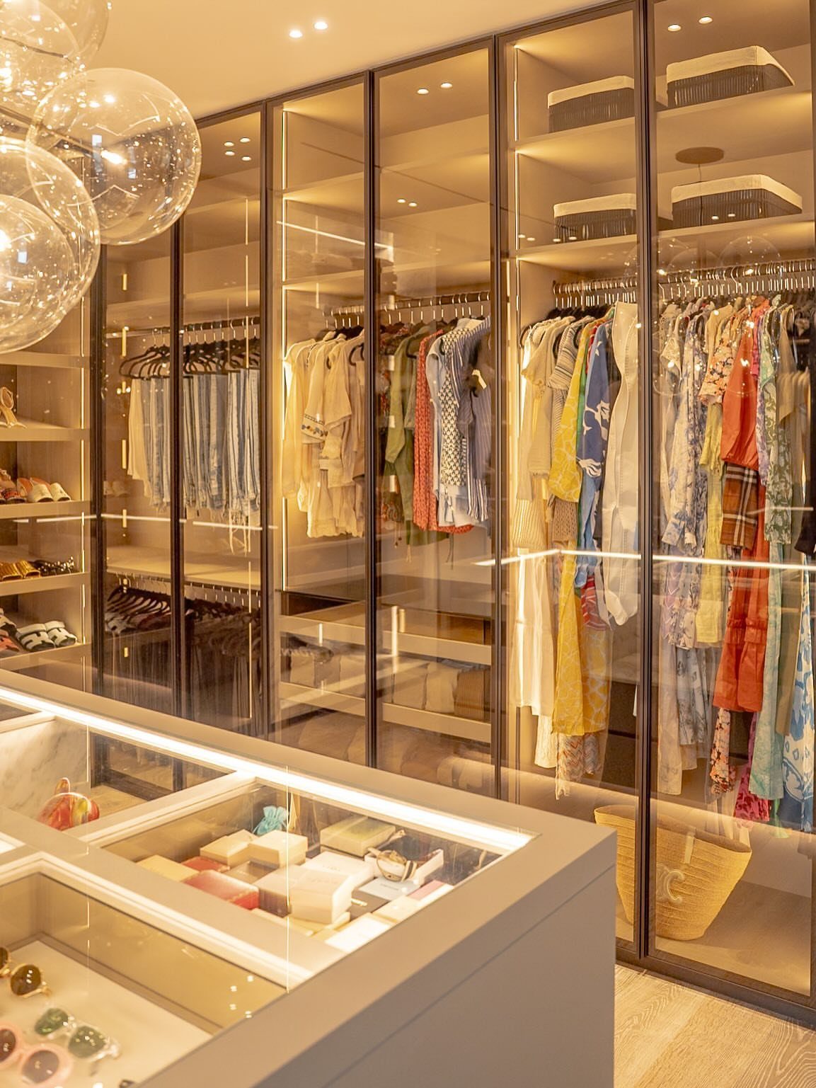 21 Closet Design Plans for Every Layout and Budget 5 Organized clothing and accessories displayed within glass-fronted luxury closet cabinets.