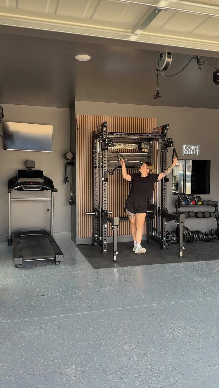 A woman posing in a modern home gym equipped with a treadmill and power rack.