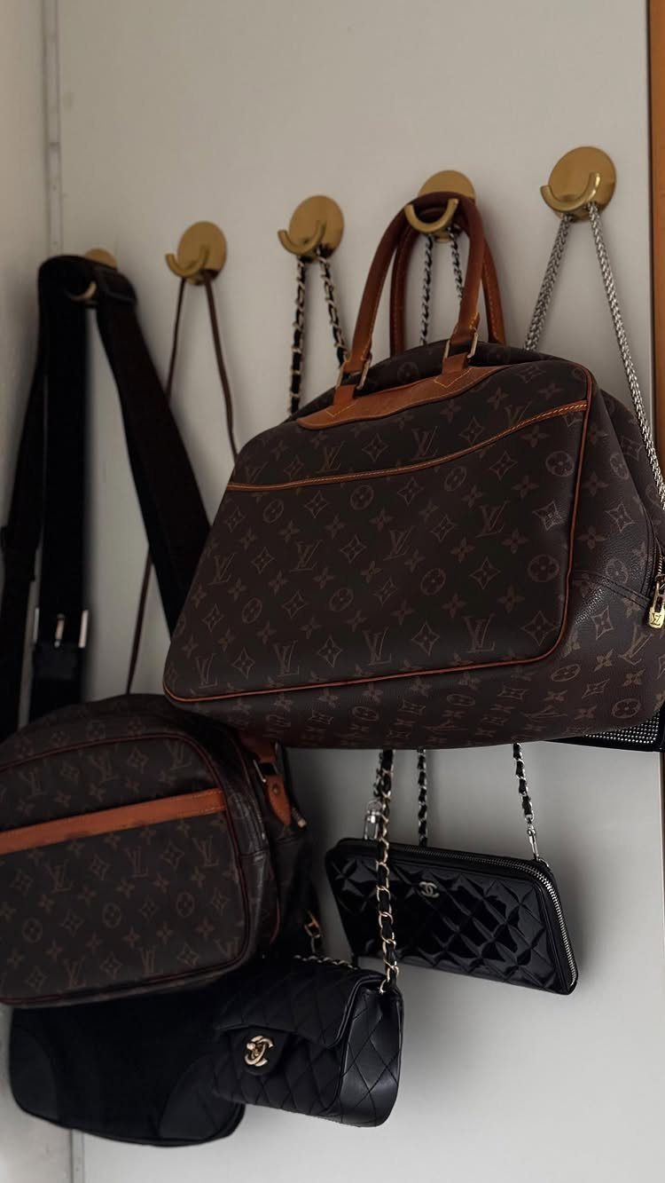 Handbag Storage and Display: 8 Ideas for Every Space 3 Designer handbags hanging from gold hooks mounted on a white wall surface.