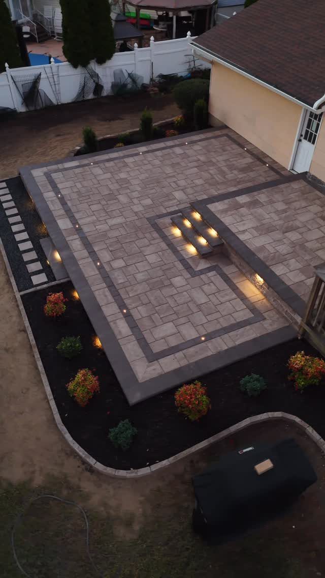 11 Flagstone Patio Design Ideas with Photos for Your Yard 7 Large flagstone patio with geometric dark grey borders and integrated outdoor lighting.