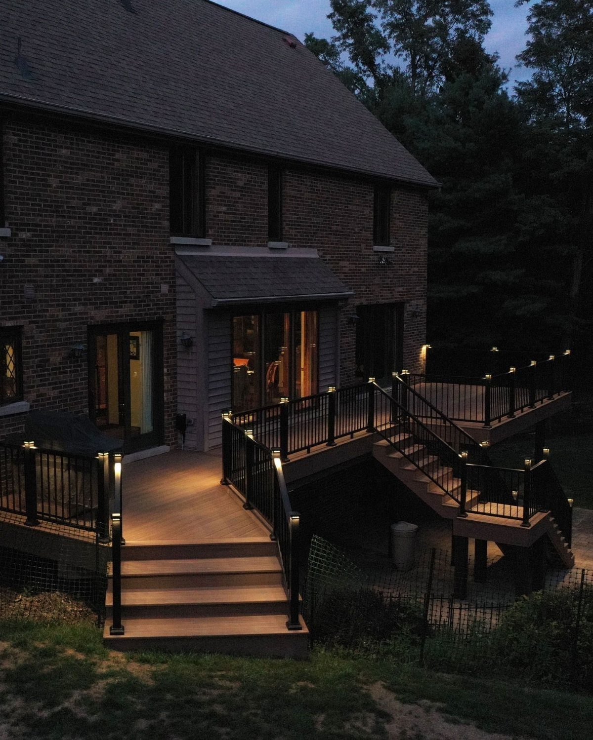 8 Ideas for Deck Accent Lighting 4 Small warm lights integrated into black metal deck railings and stairs at dusk.