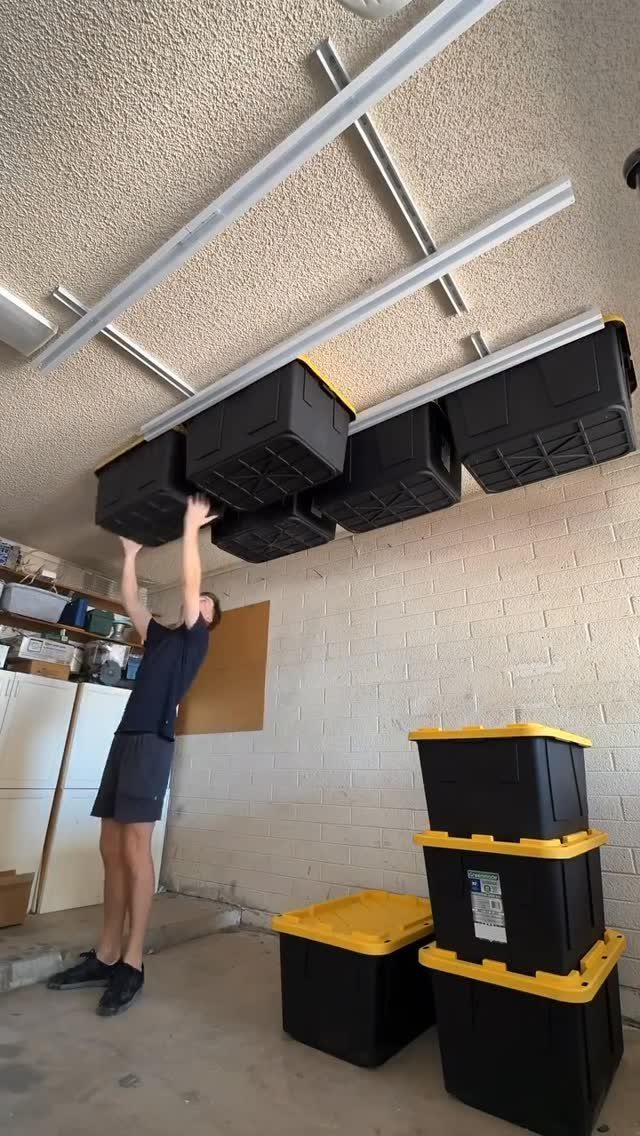 11 Tool Shed Storage Ideas for Every Wall and Corner 4 A person installing black storage bins onto a ceiling-mounted sliding track system in a garage.