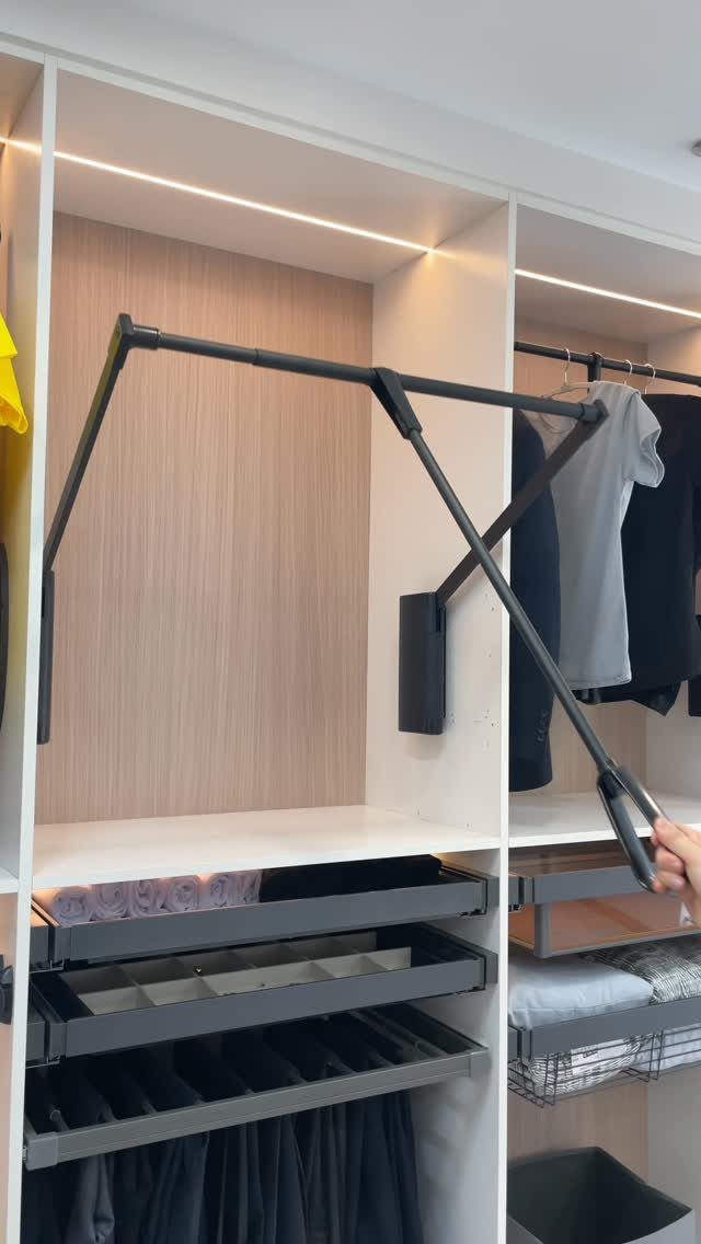 21 Closet Design Plans for Every Layout and Budget 16 A hand pulls down a black wardrobe lift mechanism inside a modern white closet system.