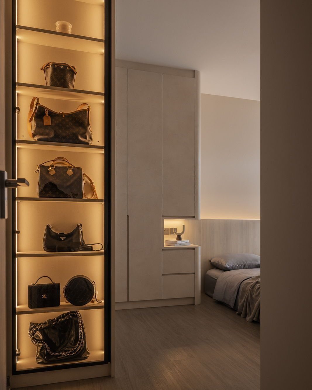 Handbag Storage and Display: 8 Ideas for Every Space 4 Luxury handbags displayed on illuminated shelves inside a tall glass-door closet cabinet.
