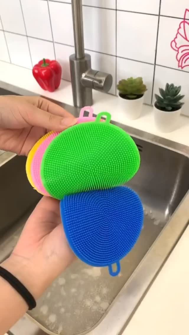 Non Toxic Kitchen Essentials: 10 Pieces That Actually Work 9 Hands holding colorful textured silicone cleaning pads over a kitchen sink.