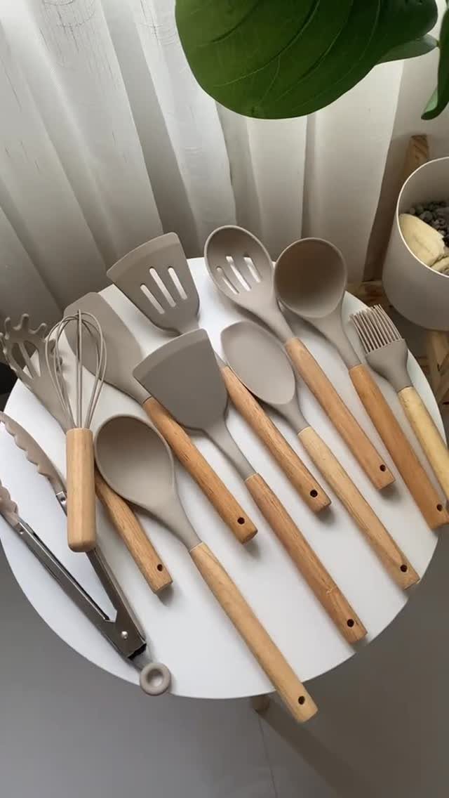 Non Toxic Kitchen Essentials: 10 Pieces That Actually Work 4 Various grey silicone kitchen utensils with wooden handles arranged on a white table.