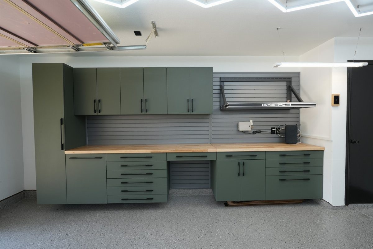 Garage Storage Modern: 12 Ideas That Free Up Floor Space 11 Modern sage green garage cabinets with a wooden countertop and slatwall storage system.