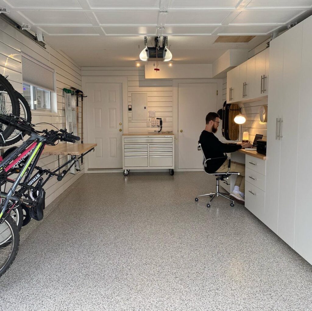 A man working at a built-in desk inside a clean, organized garage conversion.
