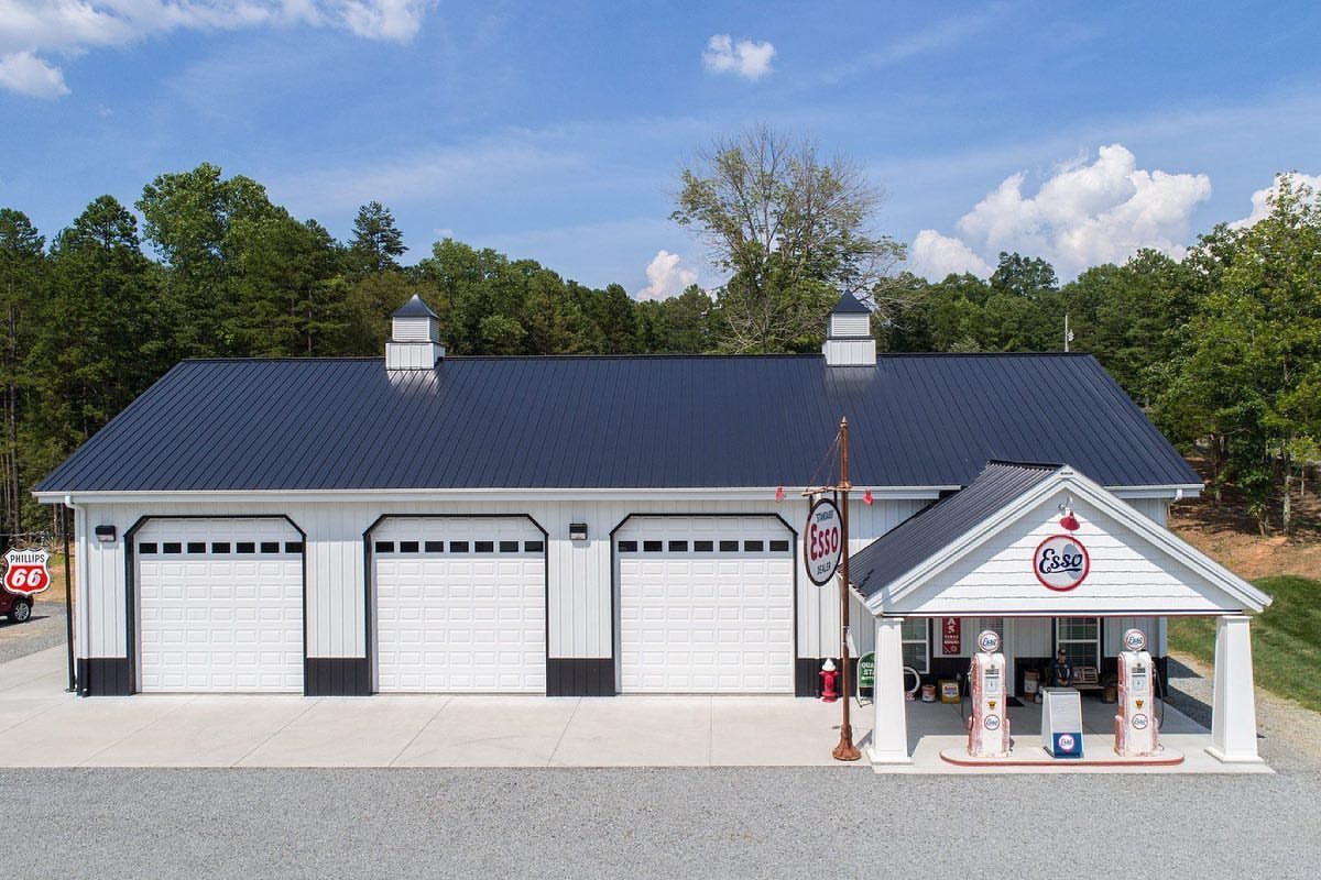 3 Car Pole Barn Garage with 6 Design Ideas 4 A white three-car pole barn garage with a dark blue roof and vintage gas pumps.